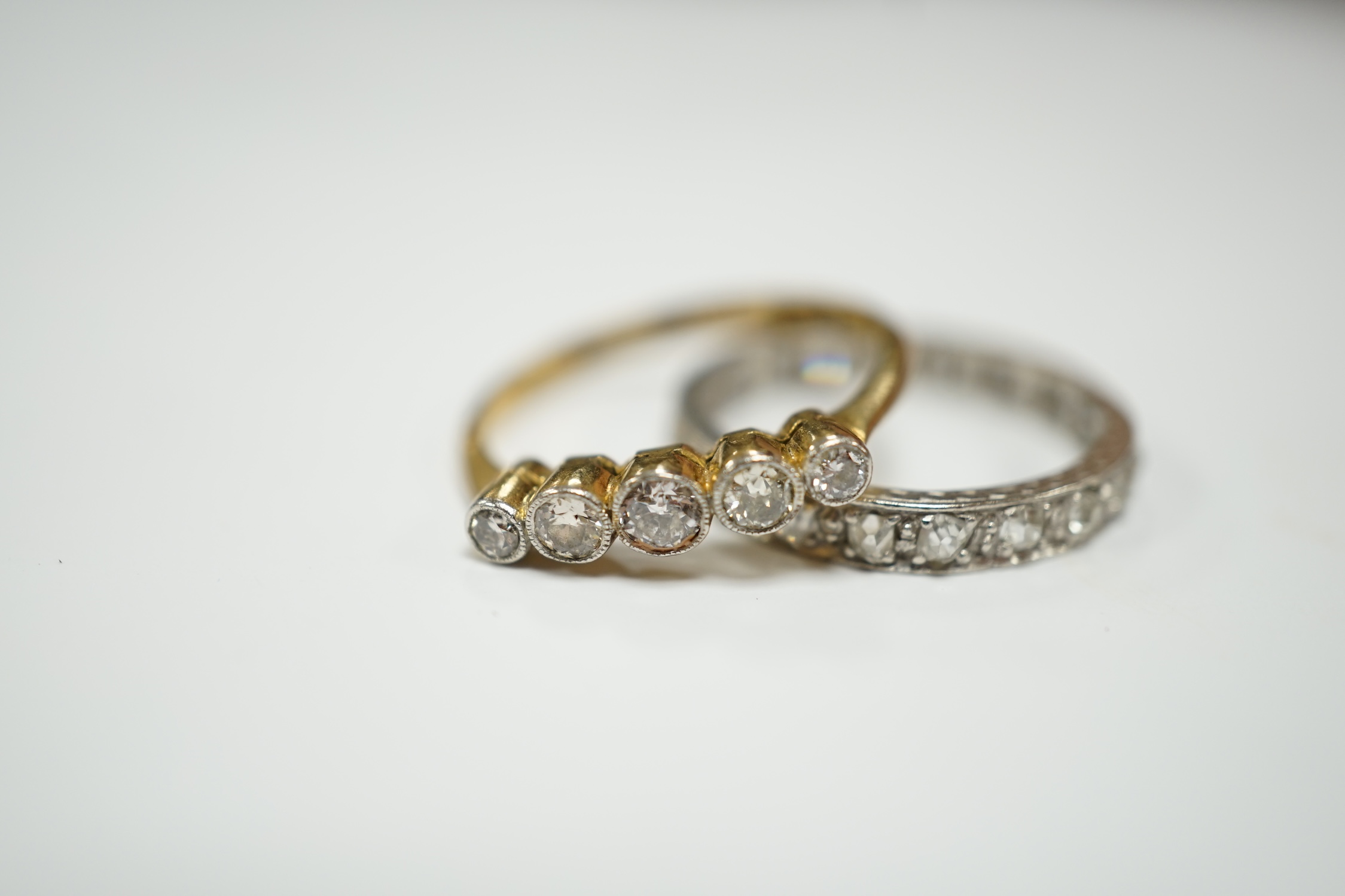 A white metal and diamond chip set full eternity ring, size L and an 18ct and graduated five stone diamond set ring, size M.